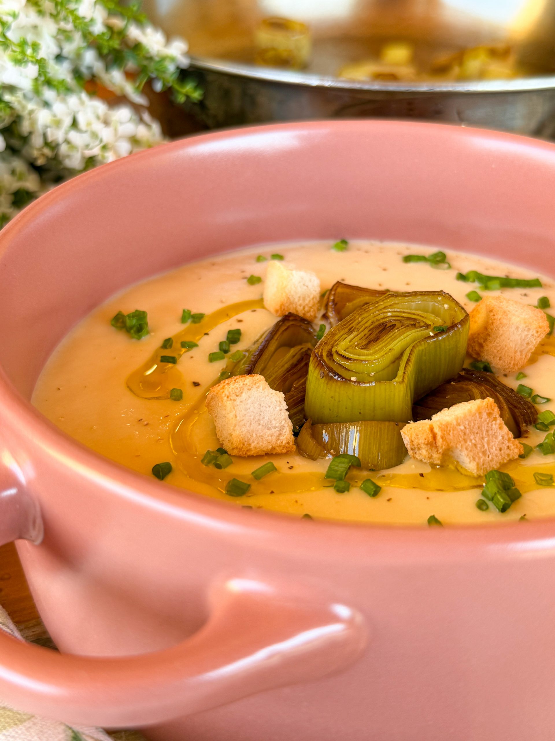 Vichyssoise casera servida en bol rosa con puerros confitados y picatostes