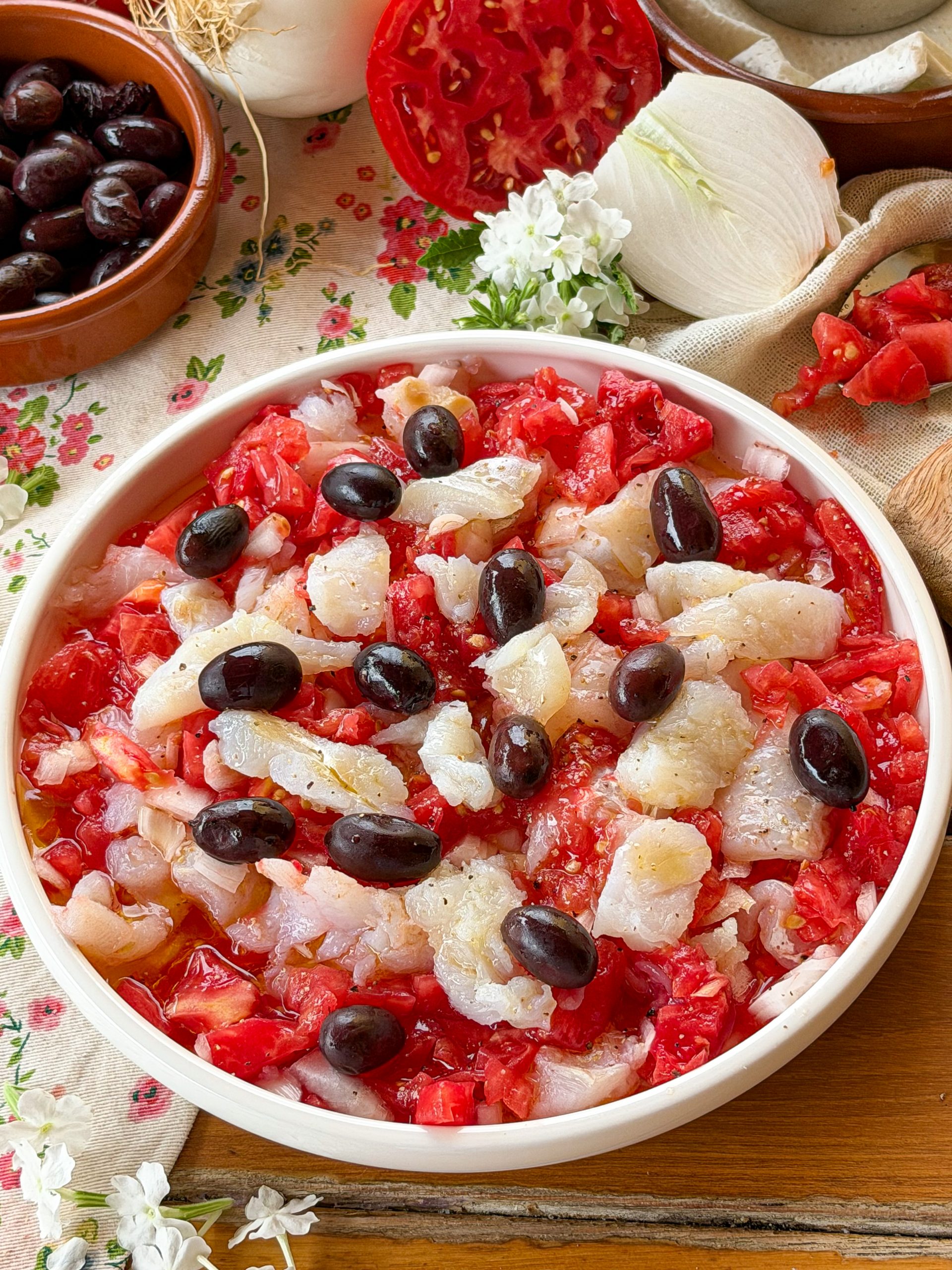 Esqueixada de bacalao catalana casera elaborada con tomate maduro, cebolla, aceitunas negras y bacalao desalado, una receta fresca típica del verano.