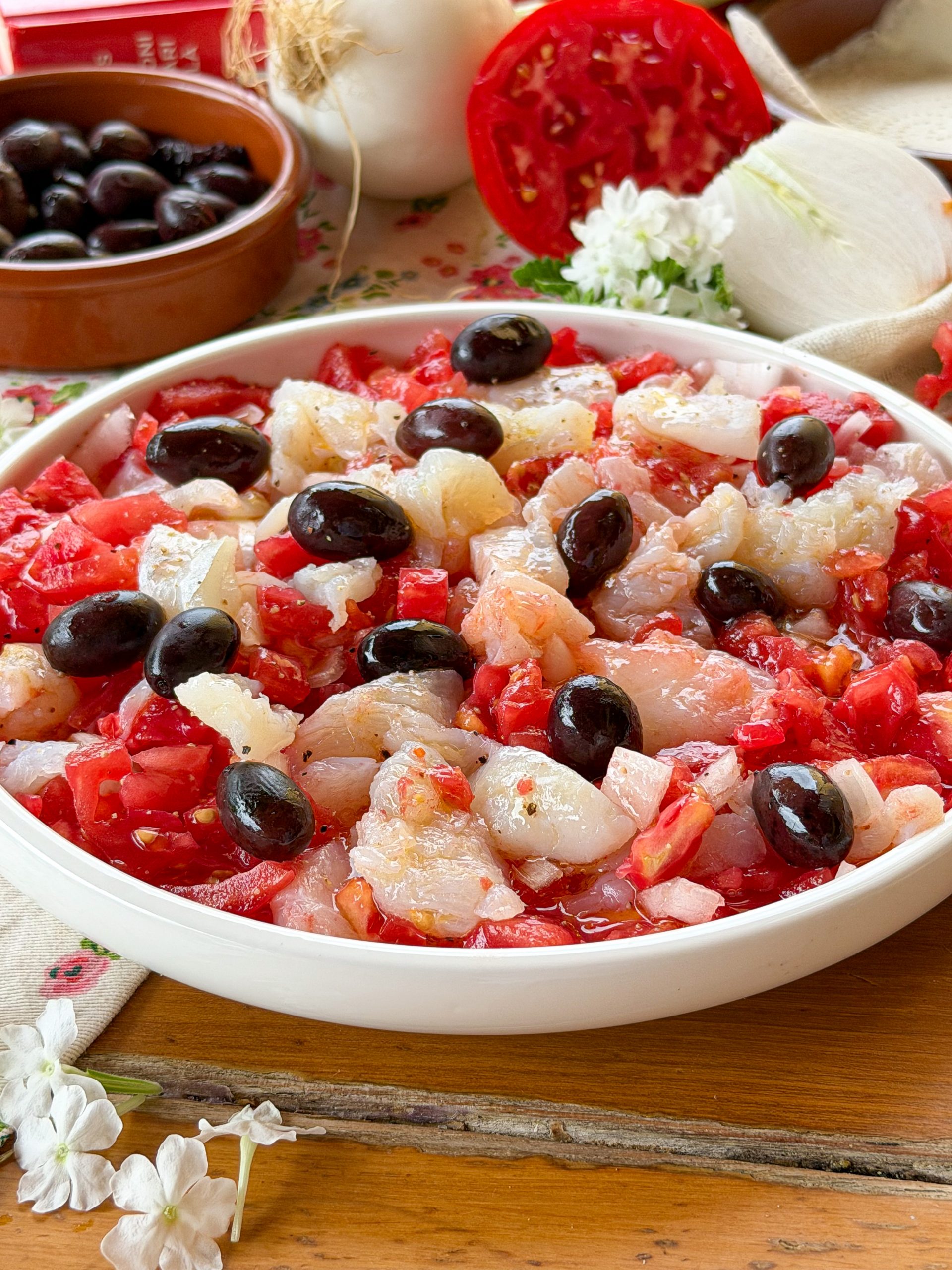 Esqueixada de bacalao catalana casera elaborada con tomate maduro, cebolla, aceitunas negras y bacalao desalado, una receta fresca típica del verano.