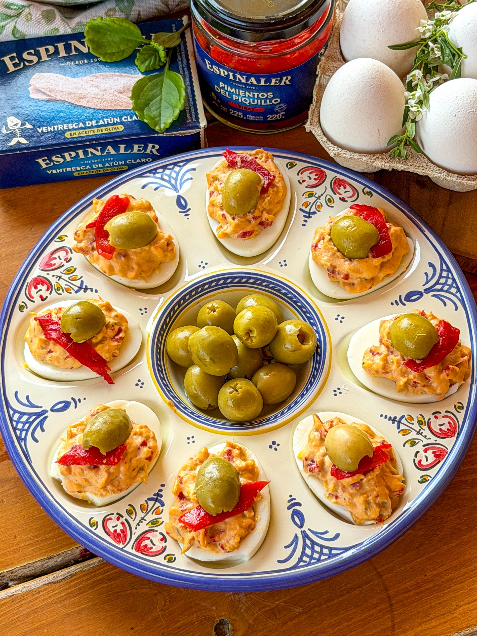 Receta de huevos rellenos de ventresca, pimientos del piquillo y aceitunas Espinaler servidos en una fuente de cerámica.