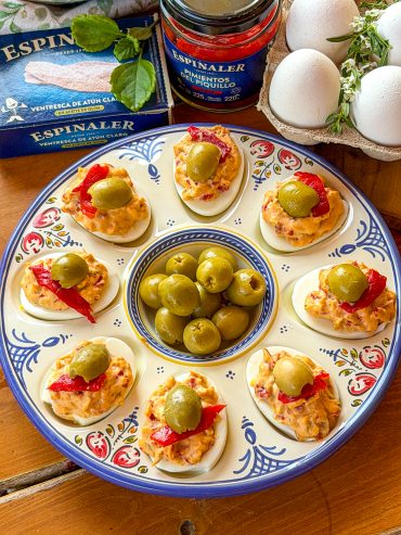 Receta de huevos rellenos de ventresca, pimientos del piquillo y aceitunas Espinaler servidos en una fuente de cerámica.
