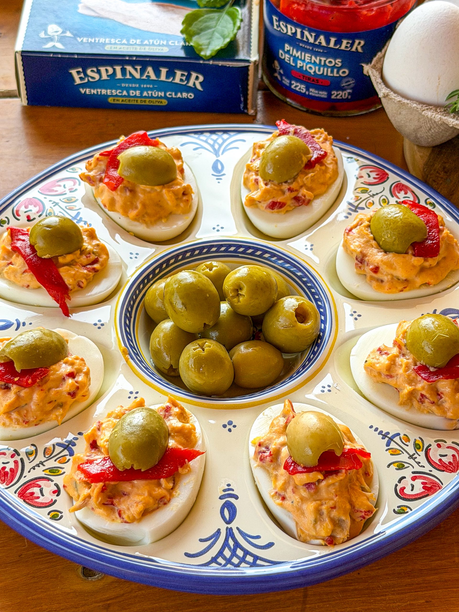 Receta de huevos rellenos de ventresca, pimientos del piquillo y aceitunas Espinaler servidos en una fuente de cerámica.