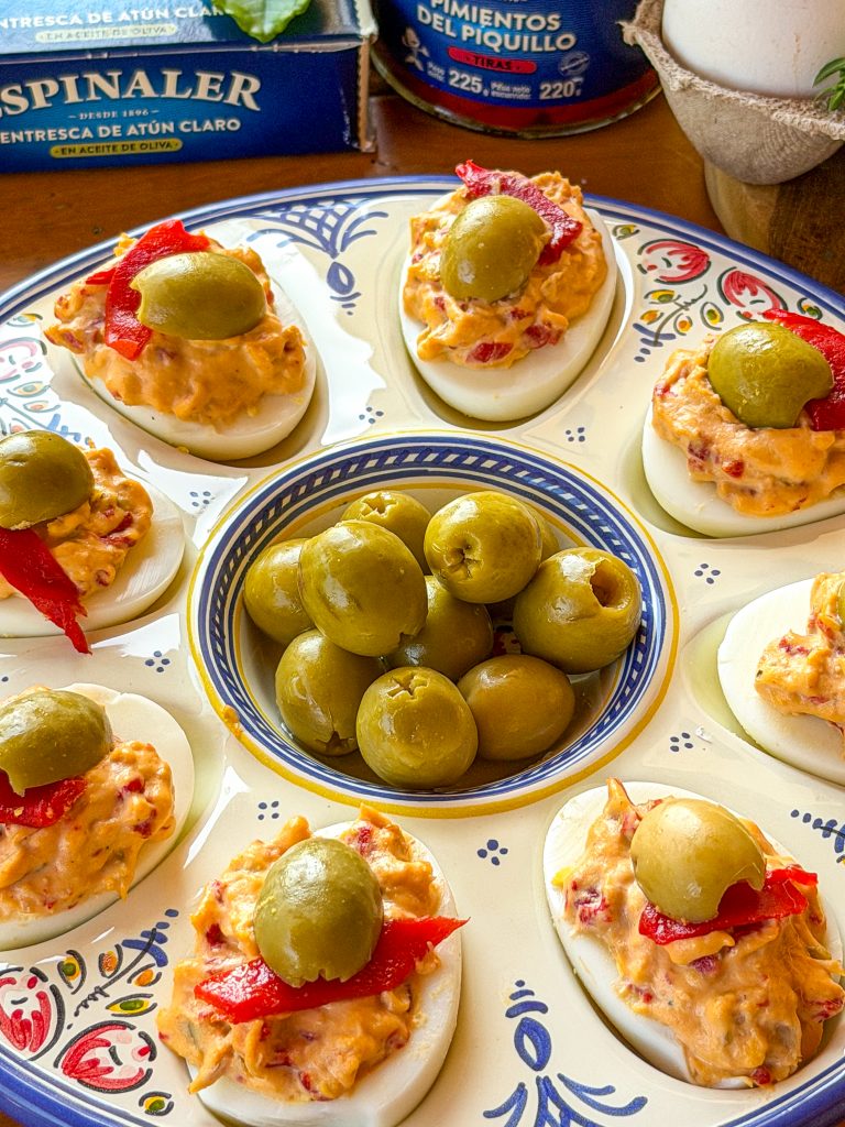 Receta de huevos rellenos de ventresca, pimientos del piquillo y aceitunas Espinaler servidos en una fuente de cerámica.