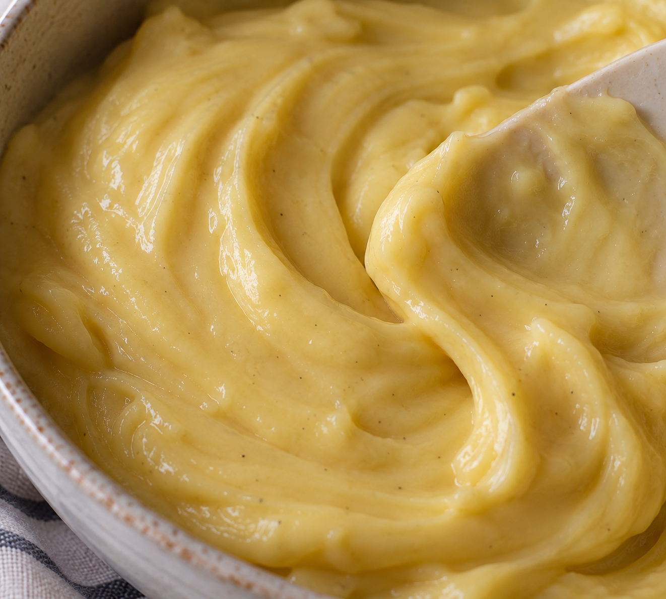 Crema pastelera casera tradicional en un cuenco de cerámica, espesa, cremosa y preparada con leche, yemas de huevo y vainilla.