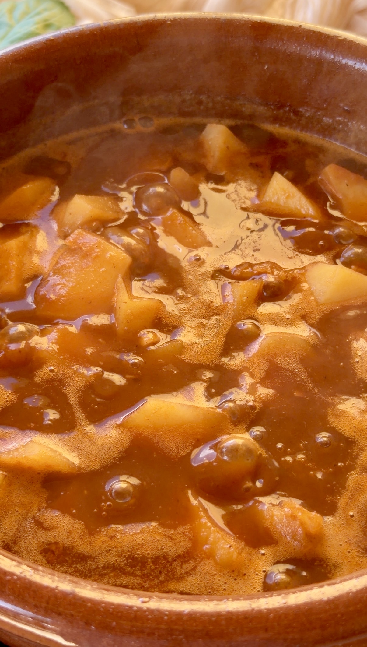 Patatas cociéndose en fumet de pescado hasta quedar tiernas en una cazuela de barro tradicional.