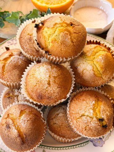 Magdalenas de naranja y chocolate esponjosas con copete alto y costra crujiente de azúcar. Receta casera fácil para preparar magdalenas de naranja jugosas con pepitas de chocolate.