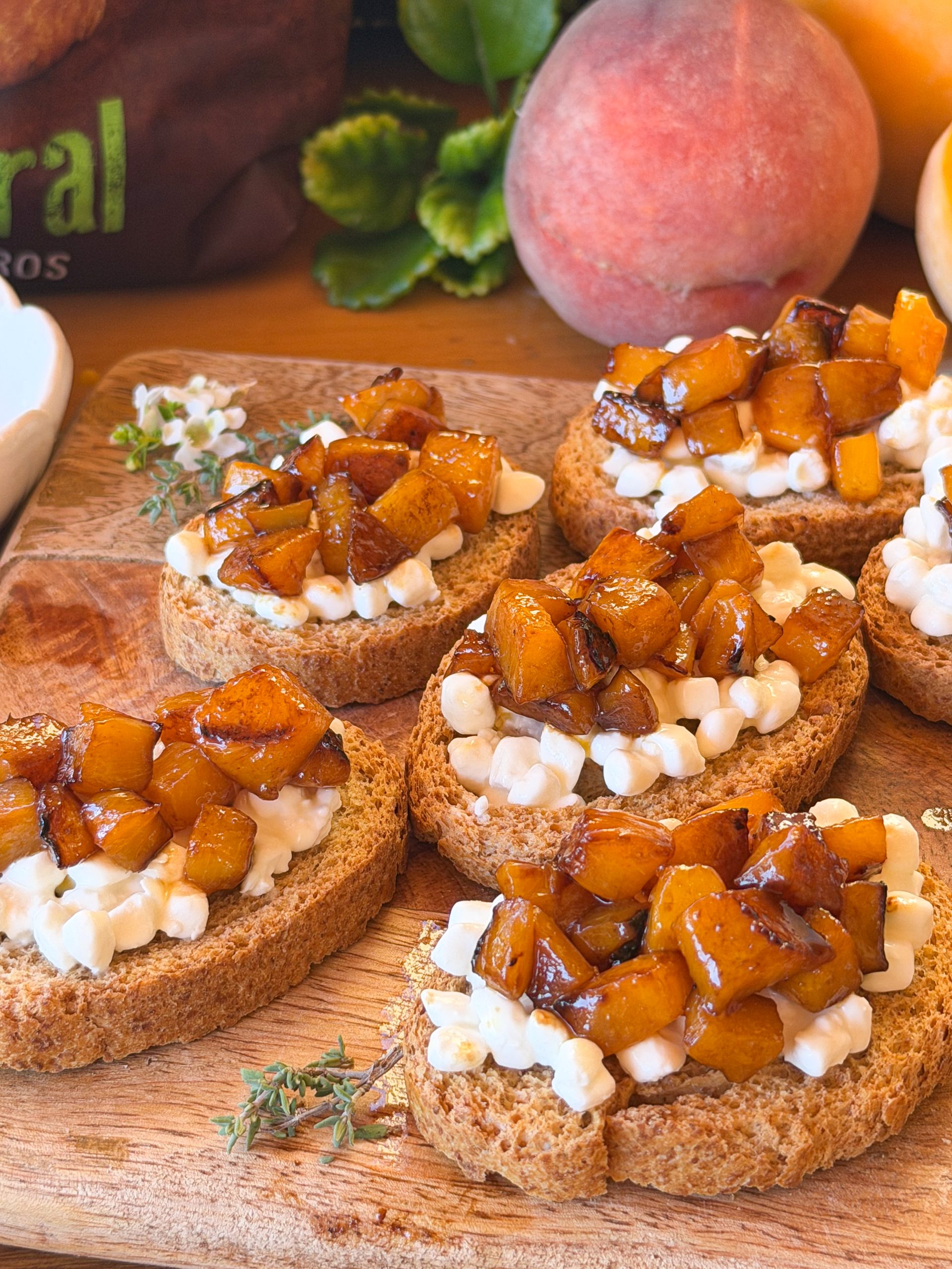 Tostadas con queso cottage y melocotón confitado sin azúcar, servidas sobre tabla de madera. Desayuno casero fácil con fruta de temporada.