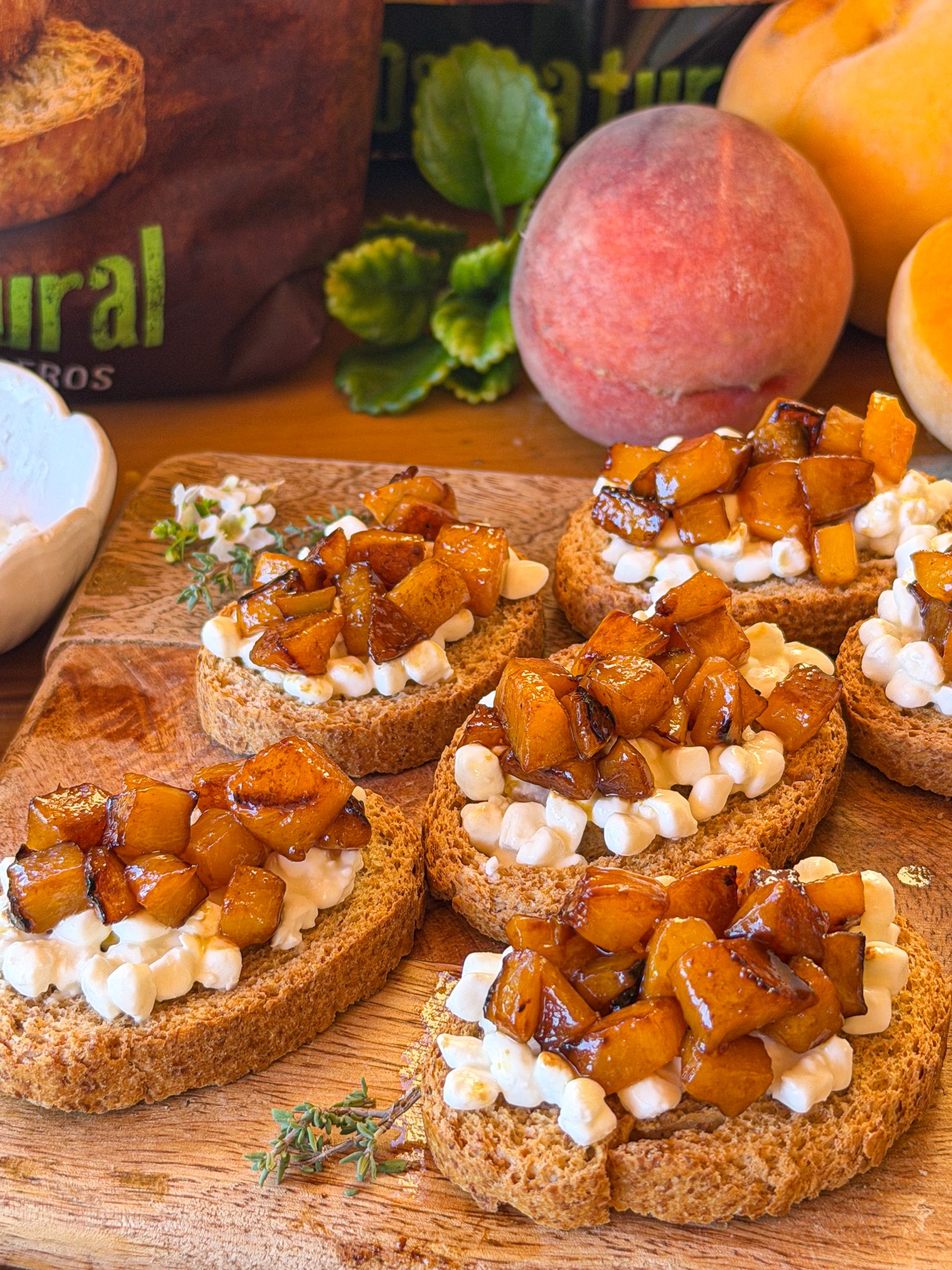 Tostadas con queso cottage y melocotón confitado sin azúcar, servidas sobre tabla de madera. Desayuno casero fácil con fruta de temporada.