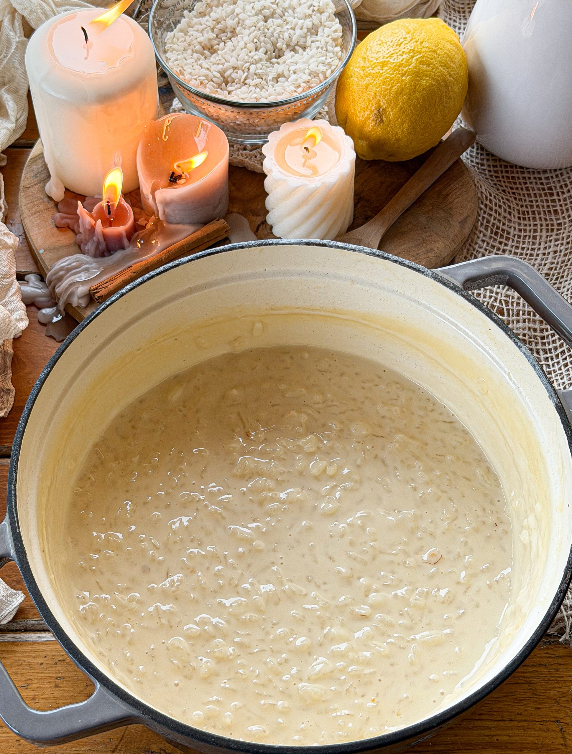 Arroz con leche cremoso en una cazuela, acompañado de arroz crudo, limón y canela en rama, ideal para una receta tradicional casera.