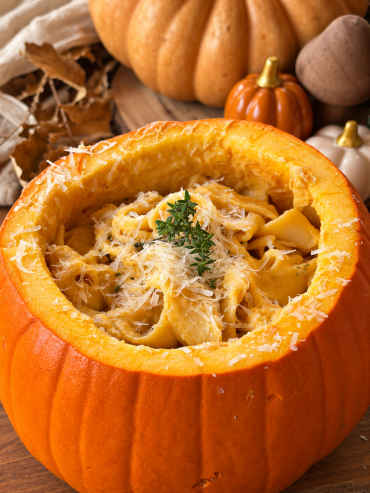Pappardelle con salsa cremosa de calabaza, queso Grana Padano y tomillo fresco servidos en una calabaza para una presentación otoñal.