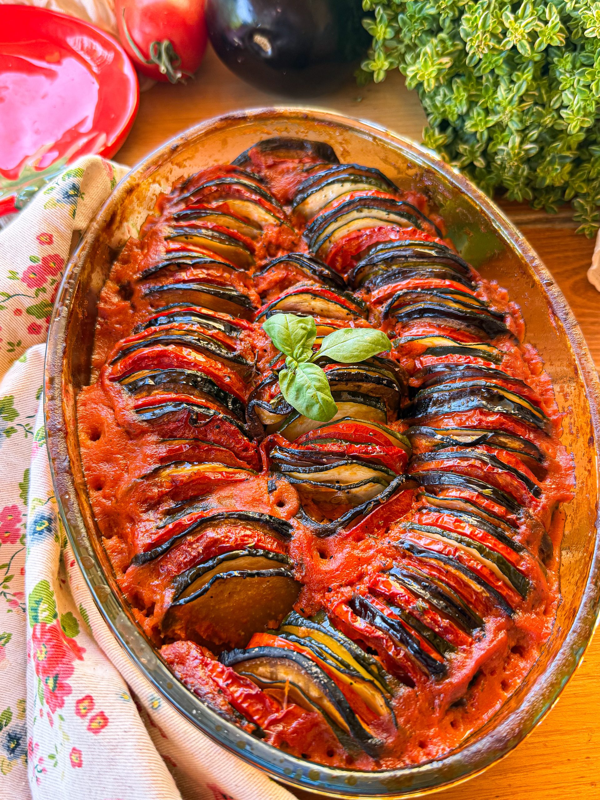 Ratatouille al horno presentada en fuente de cristal con capas de berenjena, calabacín y tomate.
